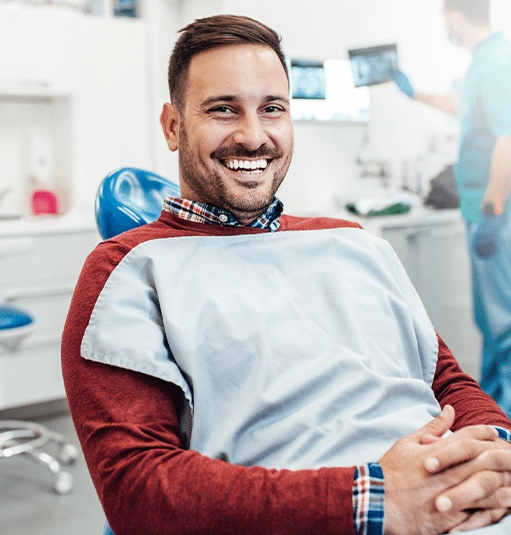 Smiling man in dental office holding child, demonstrating friendly pediatric dental care environment.