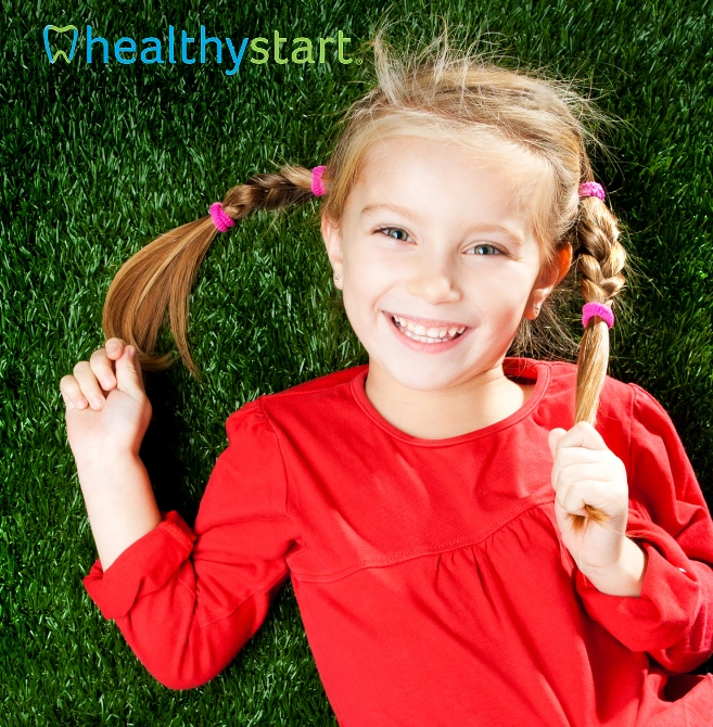 Smiling young girl with braided hair lying on grass