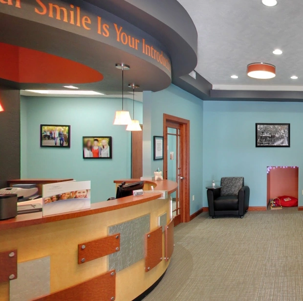 Modern dental office reception area with a front desk, chairs, and colorful interior