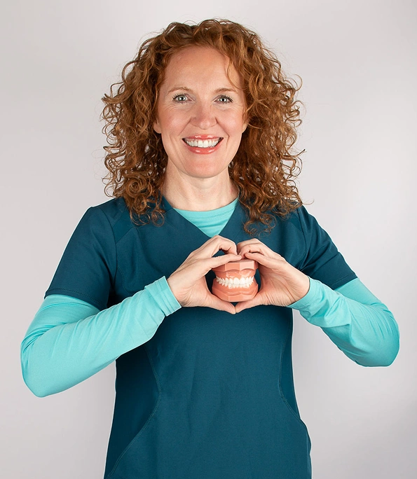 Dr. Cassondra Heinz smiling and posing in teal dental attire