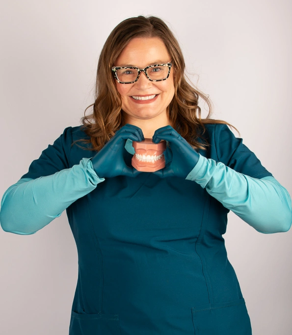 Dr. Kendra Zuercher smiling and posing in teal dental