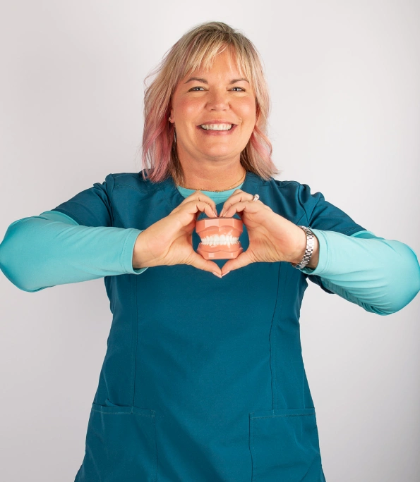 Dr. Nichole Cauwels smiling and posing in teal dental attire