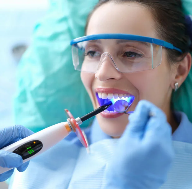 Patient in protective glasses has a dental bonding procedure with a curing light